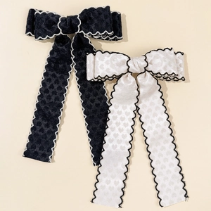 Détail de barrettes nœuds en tissu à motifs cœurs avec broderie ondulée contrastée