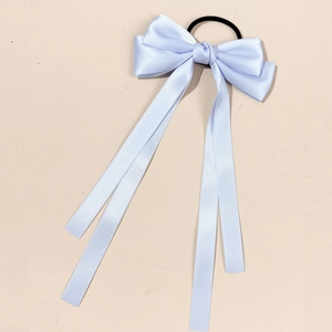 Detail of light blue satin ribbon bow hair tie with long streamers and elastic band