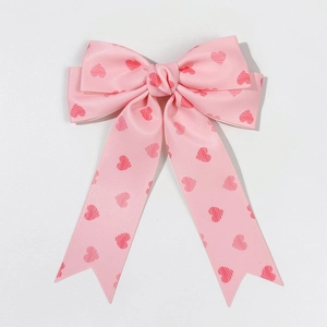 Close-up of pink heart pattern satin bow hair clip with long ribbons for girls