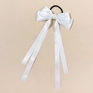 Detail of white satin bow hair tie with long ribbons and high elastic black rope