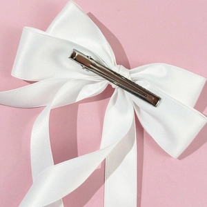 Detailed view of white silk bow hair clip with a silver metal duckbill clip back