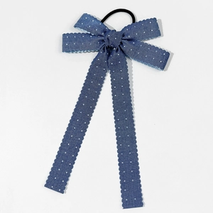 Détail d'un chouchou en jean bleu à pois blancs avec des bords ondulés et élastique