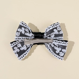 Detail of a black mesh and white lace bow hairclip with a silver alligator clip backing
