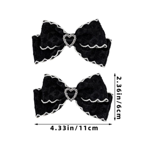 Détail de deux barrettes noeuds en dentelle noire avec cristal de coeur sur fond blanc