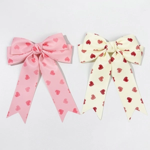 Pink and cream satin bow hair clips with red heart prints and long ribbons for sweet styling