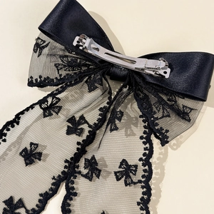 Close-up of the black satin lace bow hair clip featuring a silver metal spring back clip