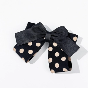 Vue détaillée de la barrette à cheveux noire à pois avec double nœud et texture côtelée