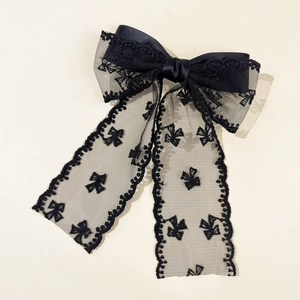Detailed view of black double-layered lace bow hair clip with intricate butterfly patterns