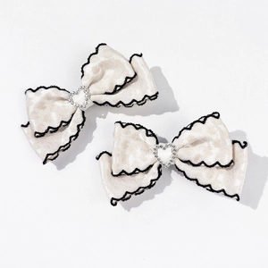 Détail de barrettes nœuds léopard crème avec cœur en strass et bordure noire ondulée