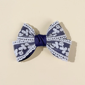 Detailed macro view of navy blue satin bow hair clip with white floral lace overlay