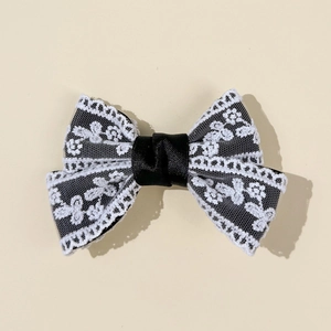 Detailed view of handmade lace bow hair clip featuring elegant black ribbon and white embroidery