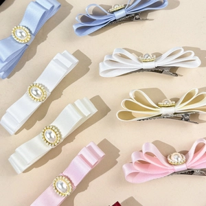 Détail de barrettes à nœuds trois couches avec perle centrale élégante et cristaux brillants