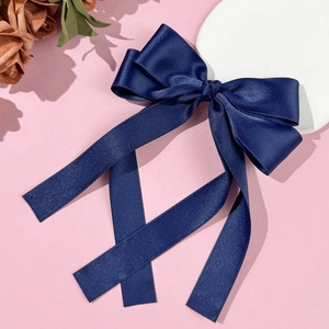 Detailed macro view of navy blue satin ribbon bow hair clip with elegant long streamers