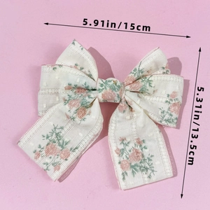 Detail of floral bow hair clip with pink roses on beige fabric and long ribbons