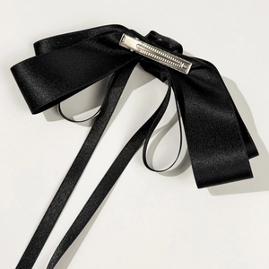 Detail of elegant black satin bow hair clip with long ribbons and metal duckbill clip