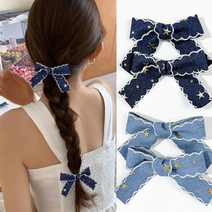 Détail des barrettes nœuds en jean avec bords ondulés et motifs d'étoiles dorées