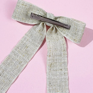 Macro detail of tweed bow hair clip back showing metallic silver alligator clip