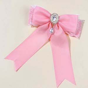 Close-up of pink lace bow hair clip with sparkling rhinestone and pearl teardrop detail