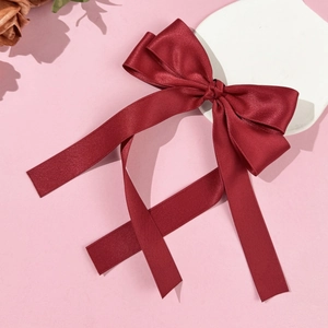 Elegant wine red satin bow hair clip with long ribbons on a pink display stand