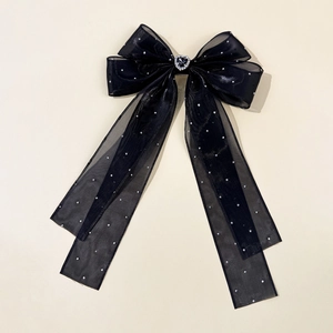 Détail d'une pince à cheveux en organza noir avec un cœur en diamant et strass argentés
