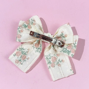 Detail of floral chiffon bow hair clip with lace edges and silver metal clip back