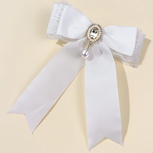 Detail of white lace bow hair clip with central rhinestone and drop pearl pendant