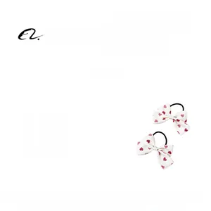 Vue détaillée d'élastiques à cheveux avec nœuds à motifs cœurs rouges sur tissu blanc doux