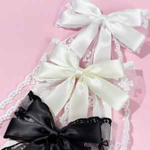 Detail showing lace and satin bow hair clips in white, beige, and black colors