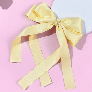 Detailed view of elegant light yellow satin ribbon bow hair clip accessory for styling