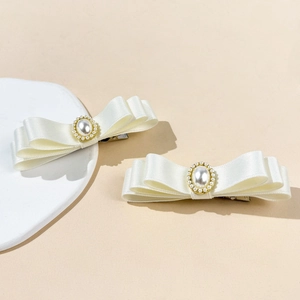 Détail des barrettes nœuds en satin blanc à trois couches avec perle et clip métallique
