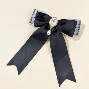 Detailed close-up of a lace bow hair clip with a rhinestone center and pearl drop pendant