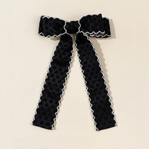 Détail du nœud papillon en velours noir avec bordure en dentelle blanche et rubans