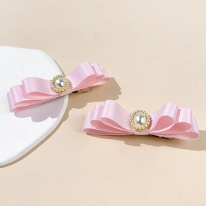Détails des barrettes à nœuds en satin rose avec perles centrales et finitions dorées