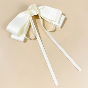 Detail of white satin bow hair clip with rose flower and elegant long flowing ribbons