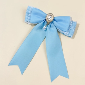Detailed close-up of light blue ribbon hair clip with lace, pearls and center gemstone