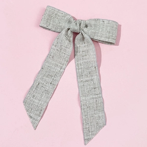 Detailed macro view of the grey linen texture and woven fabric of the bow hair clip