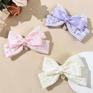 Lace bow hair clips with pearls in lavender, pink, and white on a warm background