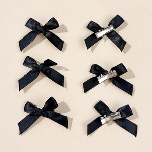 Detailed set of six black satin bow hair clips showing front fabric and back metal grip