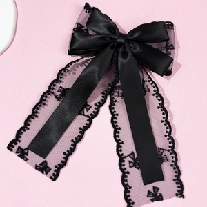 Detail of elegant black lace bow hair clip with embroidered patterns and satin finish