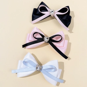 Close-up of layered satin bow hair clips featuring a central heart-shaped rhinestone