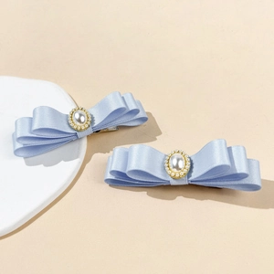 Détail de barrettes nœuds bleu clair à trois couches avec perle centrale et perles dorées