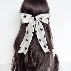 Detail of white satin hair clip with black heart patterns and wavy mesh lace trim
