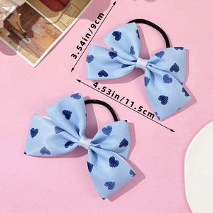 Détail du chouchou nœud bleu clair avec motifs de cœurs foncés sur fond rose