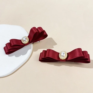 Détail de barrettes à nœuds en satin de soie bordeaux avec perles ovales centrales élégantes