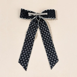 Détail du clip crocodile sur nœud papillon noir avec dentelle et motifs de cœurs gris