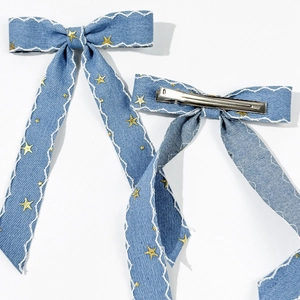 Détail de barrettes en denim avec étoiles dorées et pinces crocodiles en métal