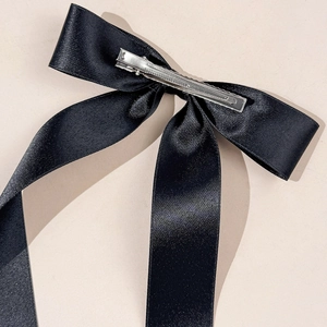 Détail d'un nœud papillon en satin noir avec longs rubans et pince à cheveux en métal