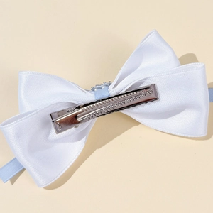Detail view of white satin bow hair clip with blue ribbon and sparkling rhinestone accents