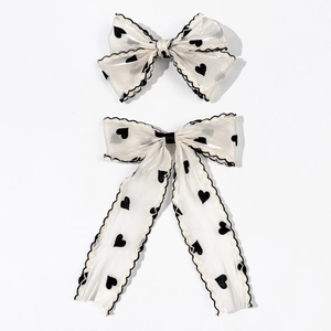 Elegant off-white bow hair clip set with black heart patterns and delicate lace edges