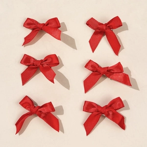 Set of 6 glossy red satin ballet bow hair clips neatly arranged on a beige background